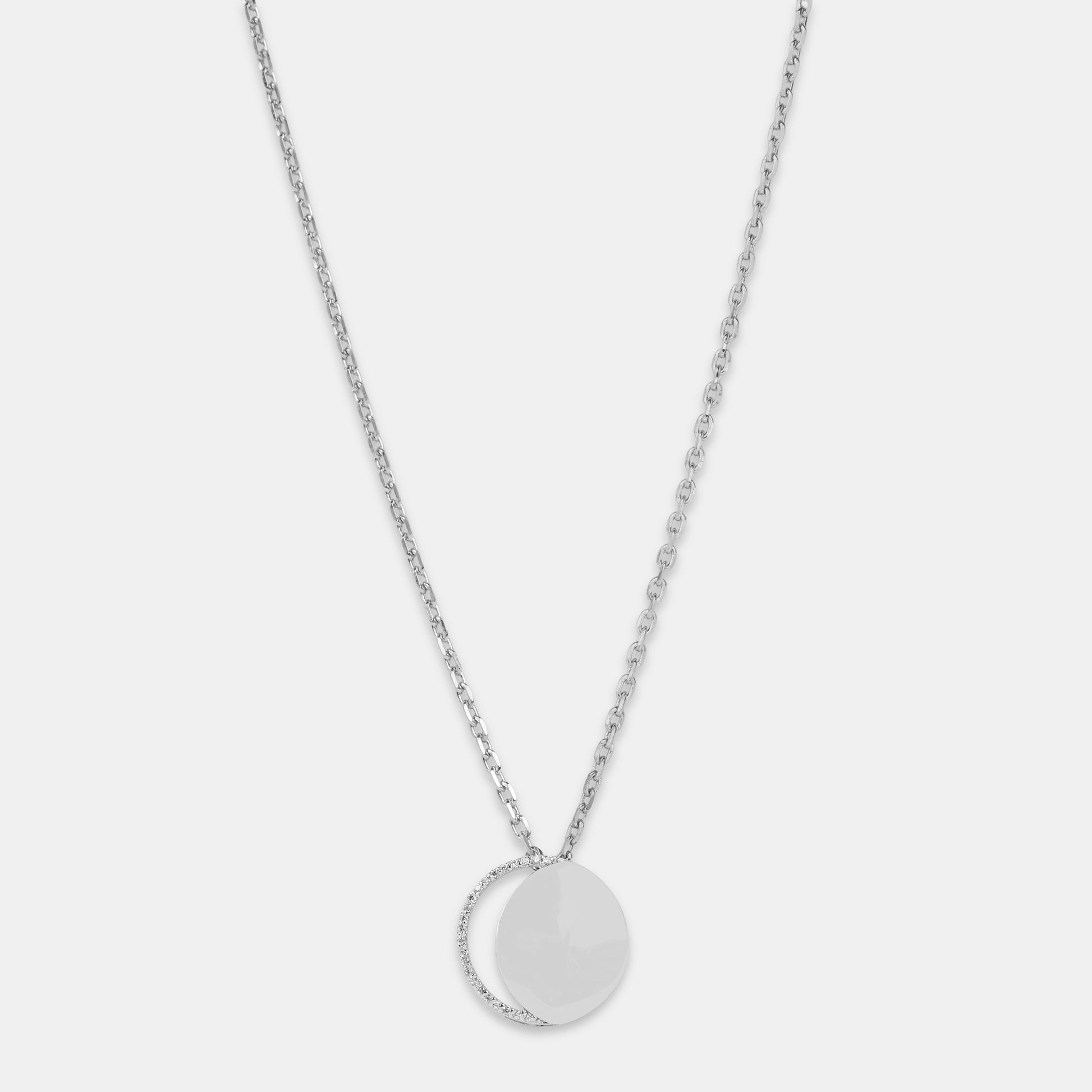 Silver necklace with diamonds in a circular pendant representing the waxing crescent moon on a light gray background