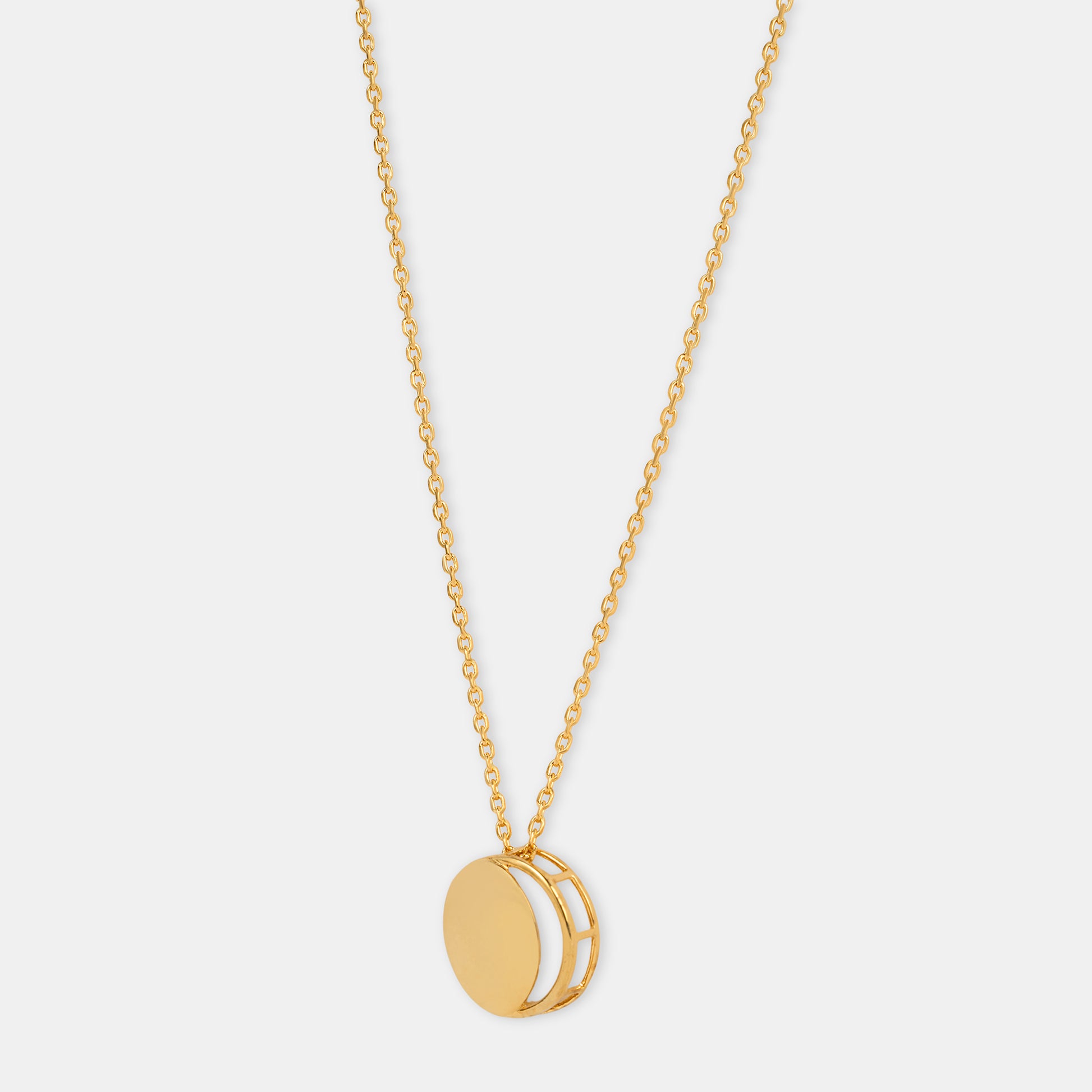 Gold necklace with a circular pendant representing the waxing crescent moon on a light gray background