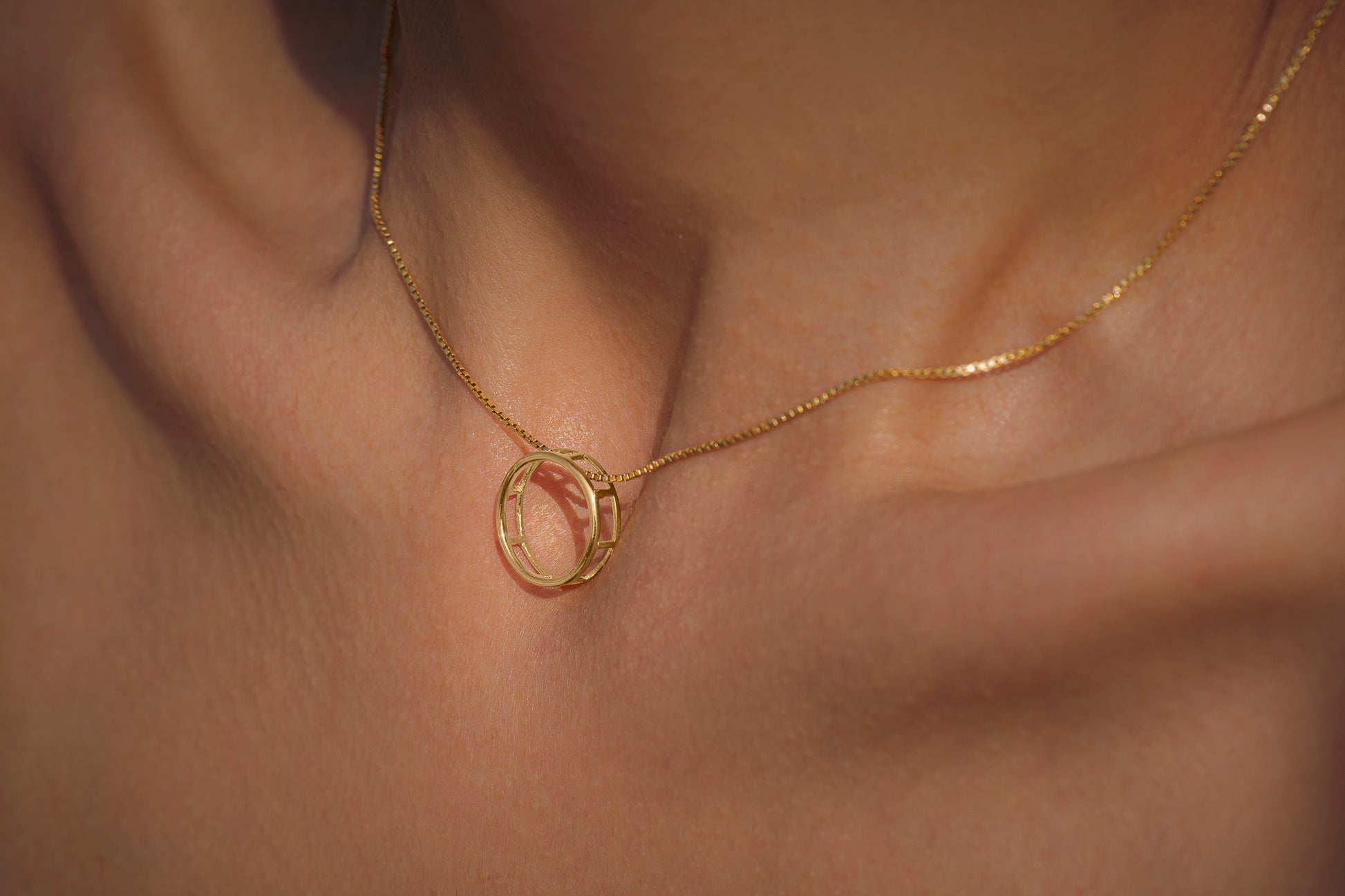 Gold necklace with a unique full moon pendant on skin