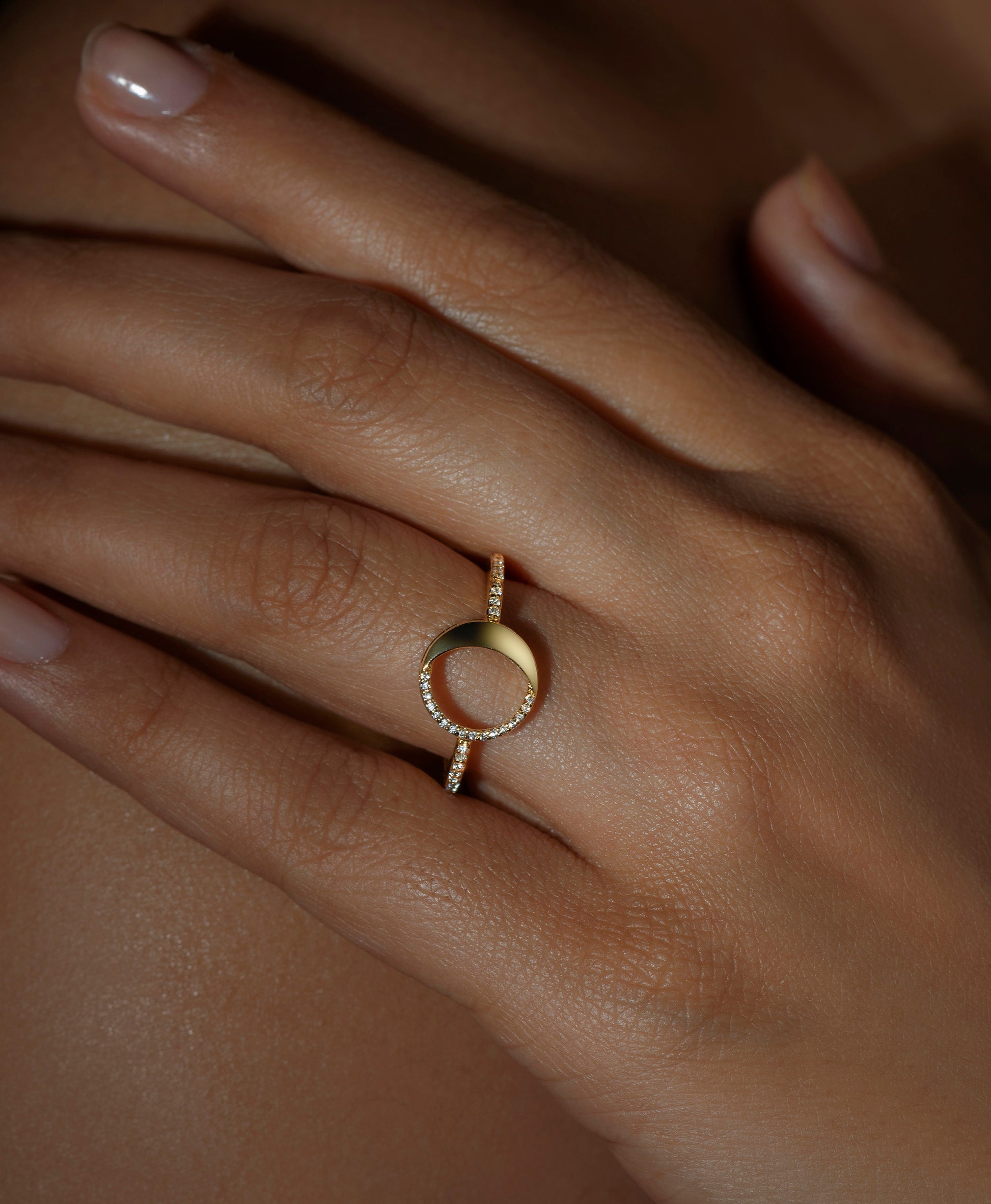A person wearing a ring with a waning gibbous phase design, crafted from sterling silver with a high polish finish, featuring American diamonds.