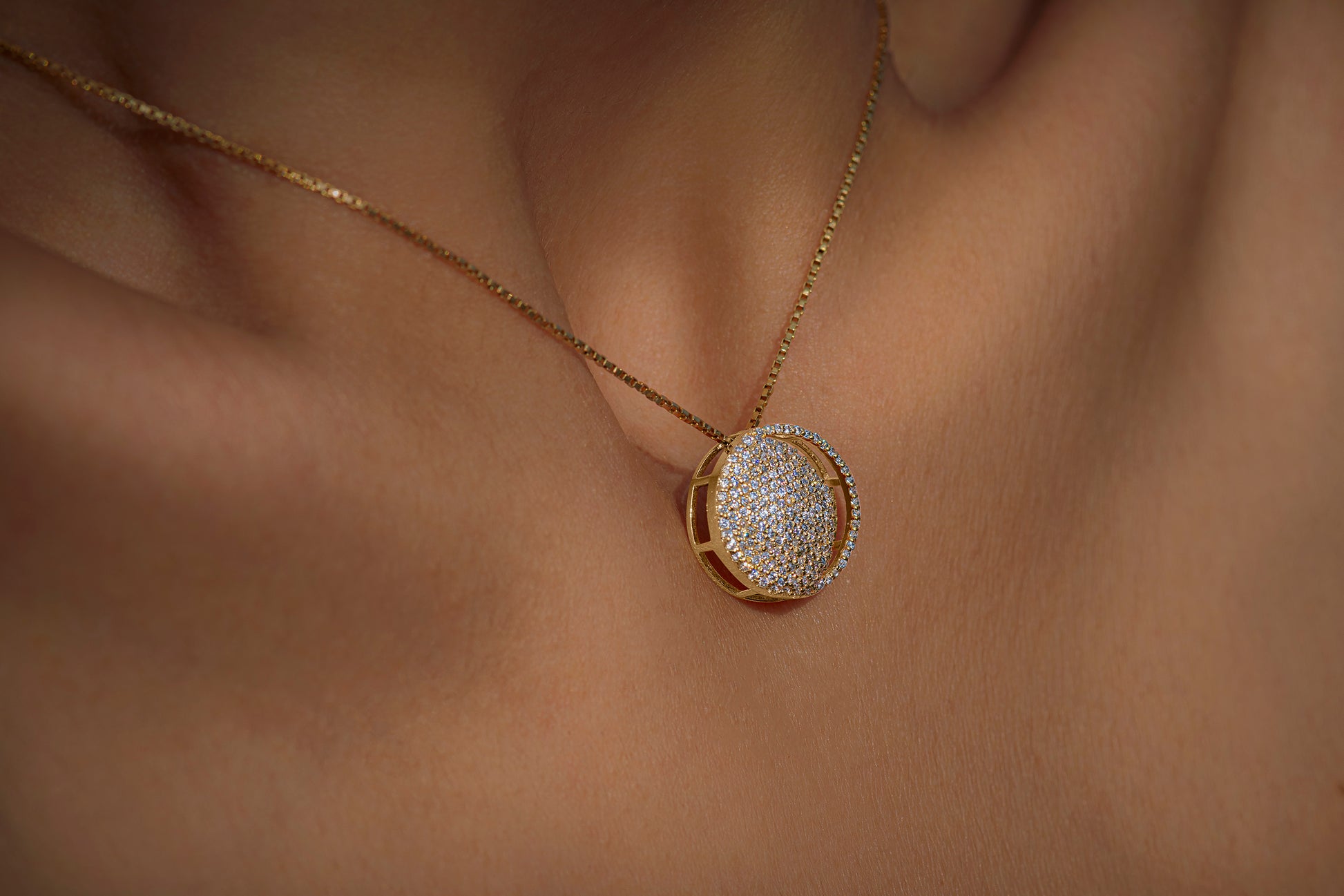 A waxing crescent moon-shaped pendant necklace with a high polish finish, adorned with American diamonds, displayed on a person's neck.