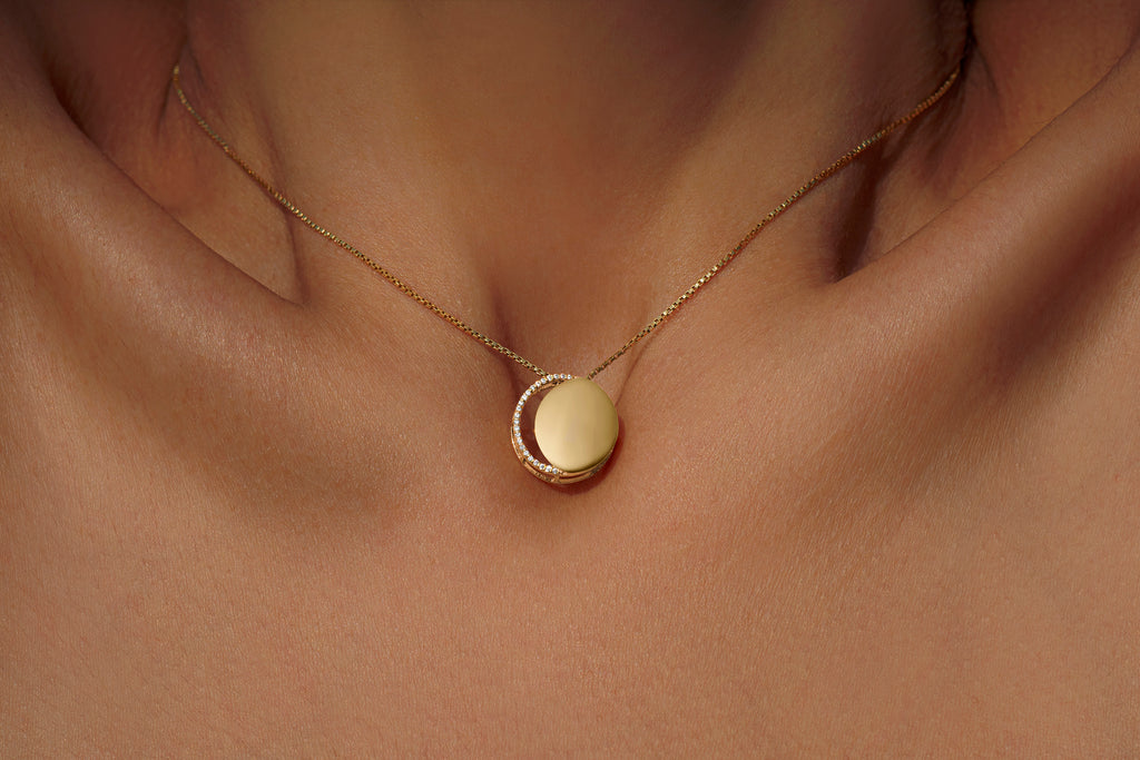 Gold necklace with diamonds in a circular pendant representing the waxing crescent moon on model
