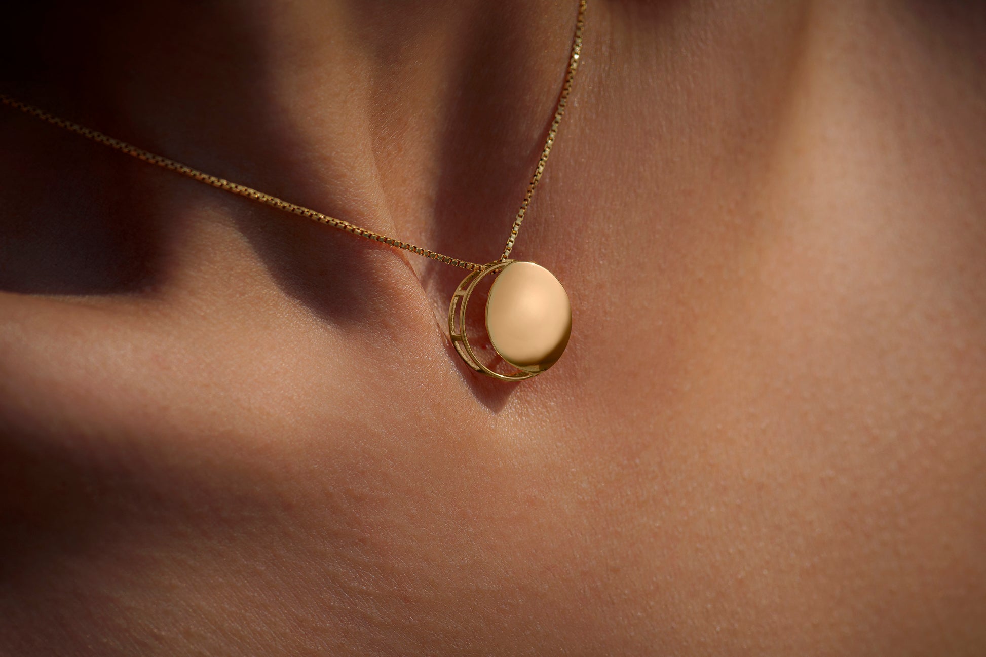 Gold necklace with a circular pendant representing the waxing crescent moon on model