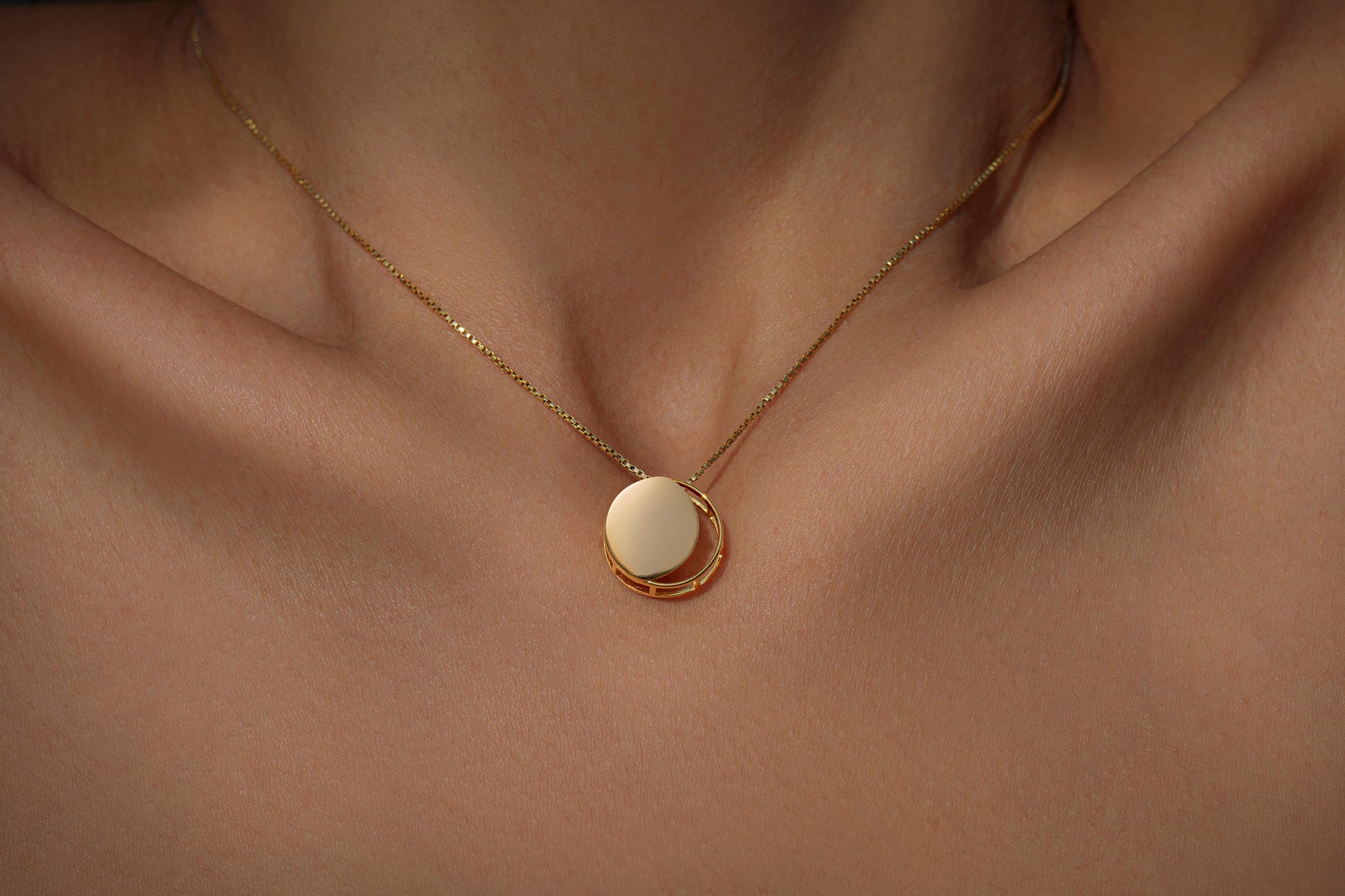 Gold necklace with a circular pendant representing the waxing crescent moon on model