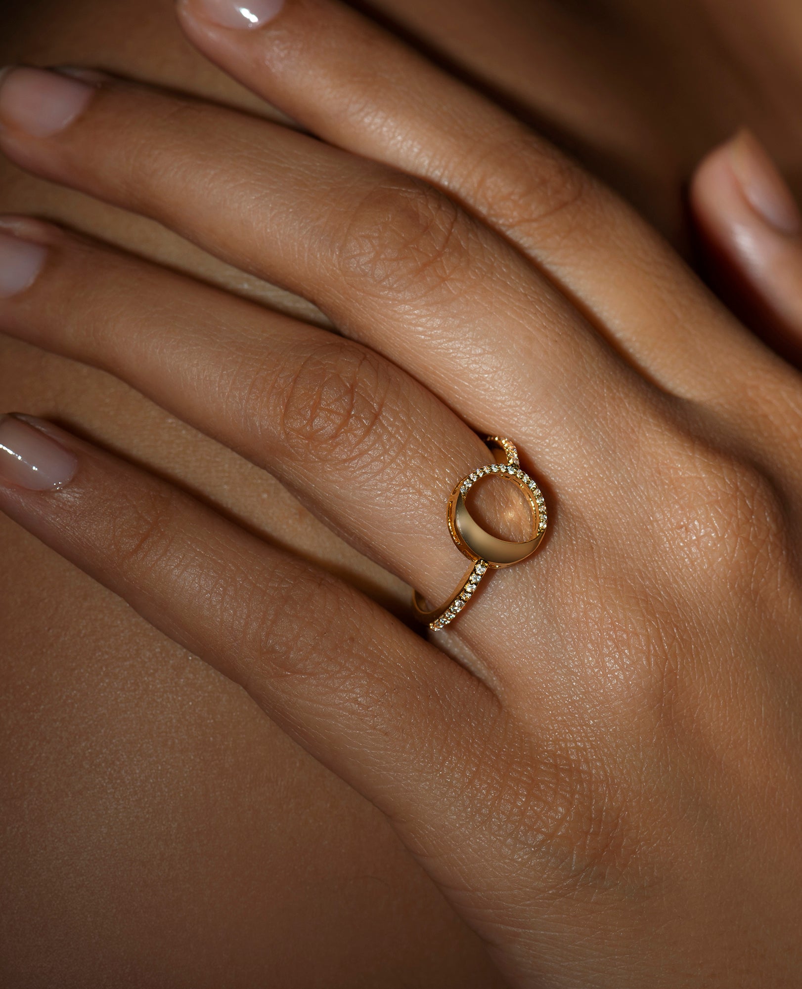 A person wearing a ring with a waning gibbous phase design, crafted from sterling silver with a high polish finish, featuring American diamonds.