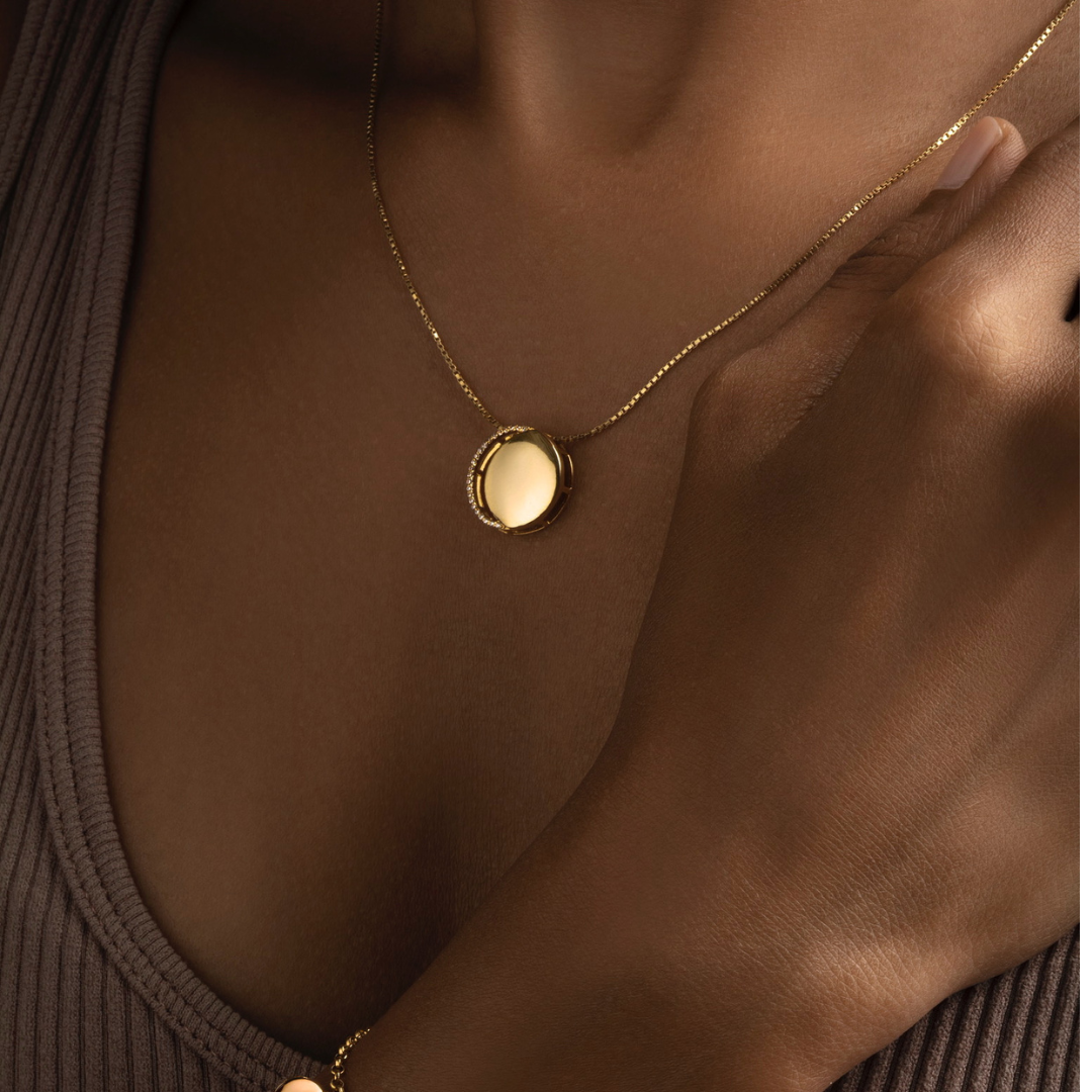 Gold necklace with diamonds in a circular pendant representing the waxing crescent moon on model